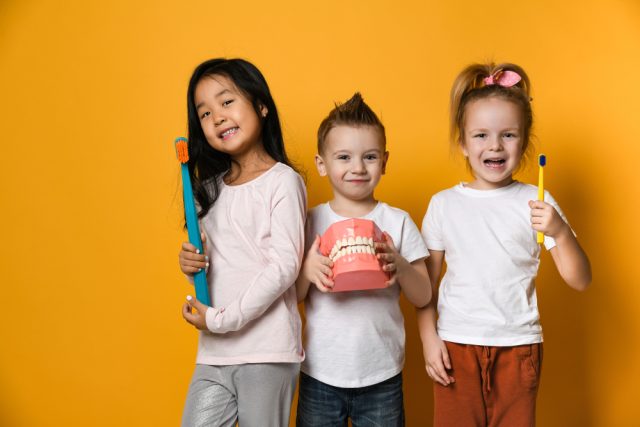 three children holding dental models