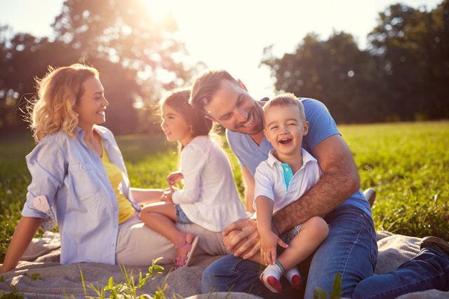 family of four sitting outside on a picnic