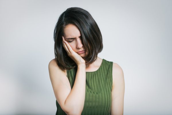 woman cradling her cheek from tooth pain